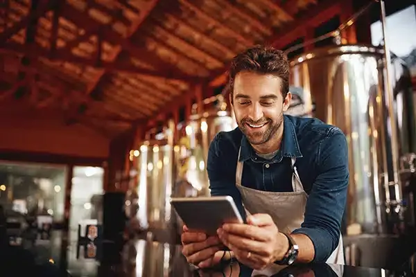 man smiling looking at tablet in restaurant.